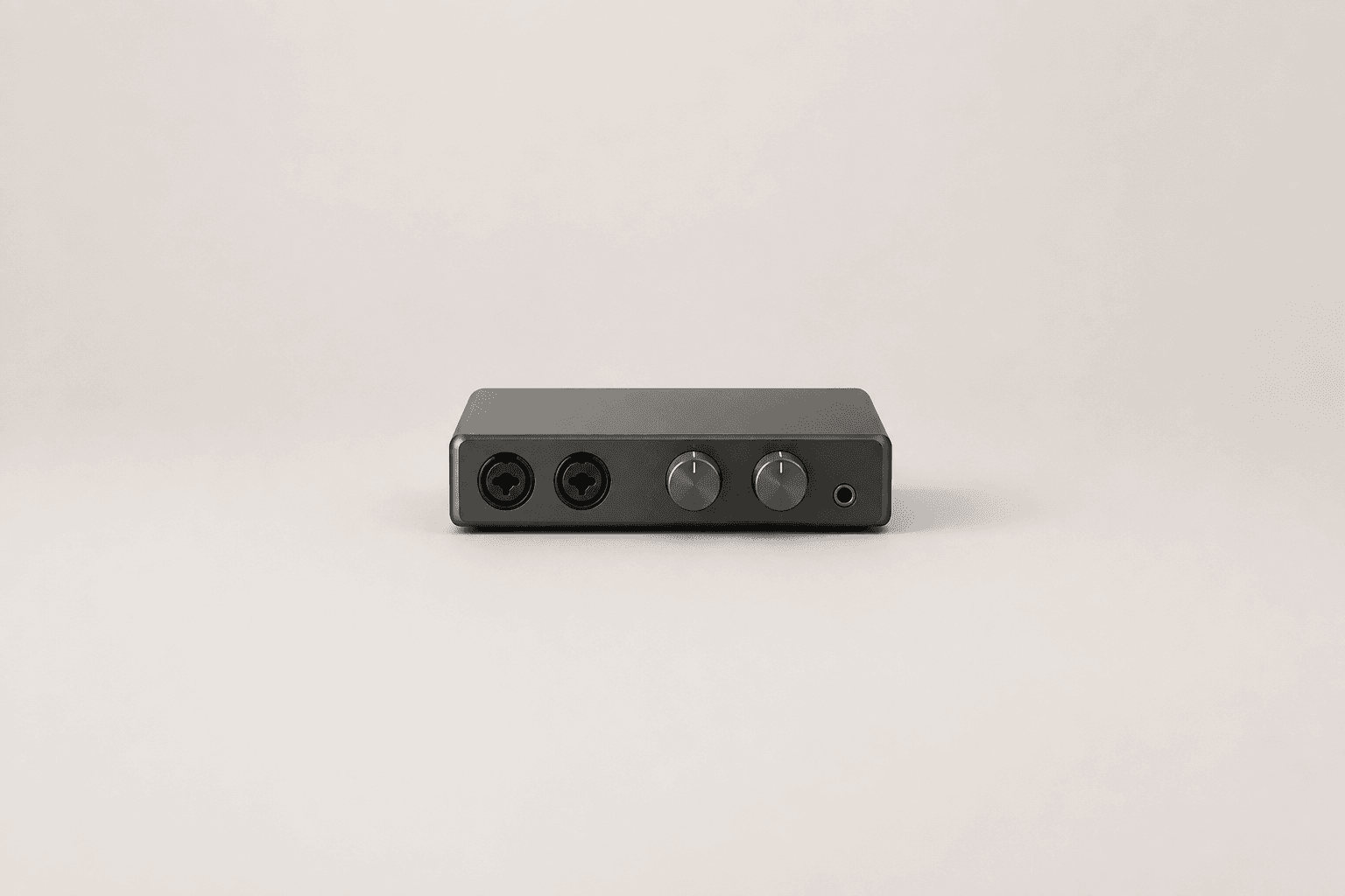 A small two-channel desktop audio interface with two round gain knobs and two combo input sockets, centred on a plain pale grey surface with empty space around it
